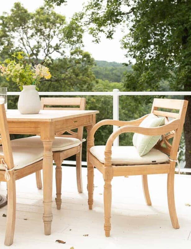 柚木树木家具用餐在有玻璃栏杆的一个白色露台设置了。