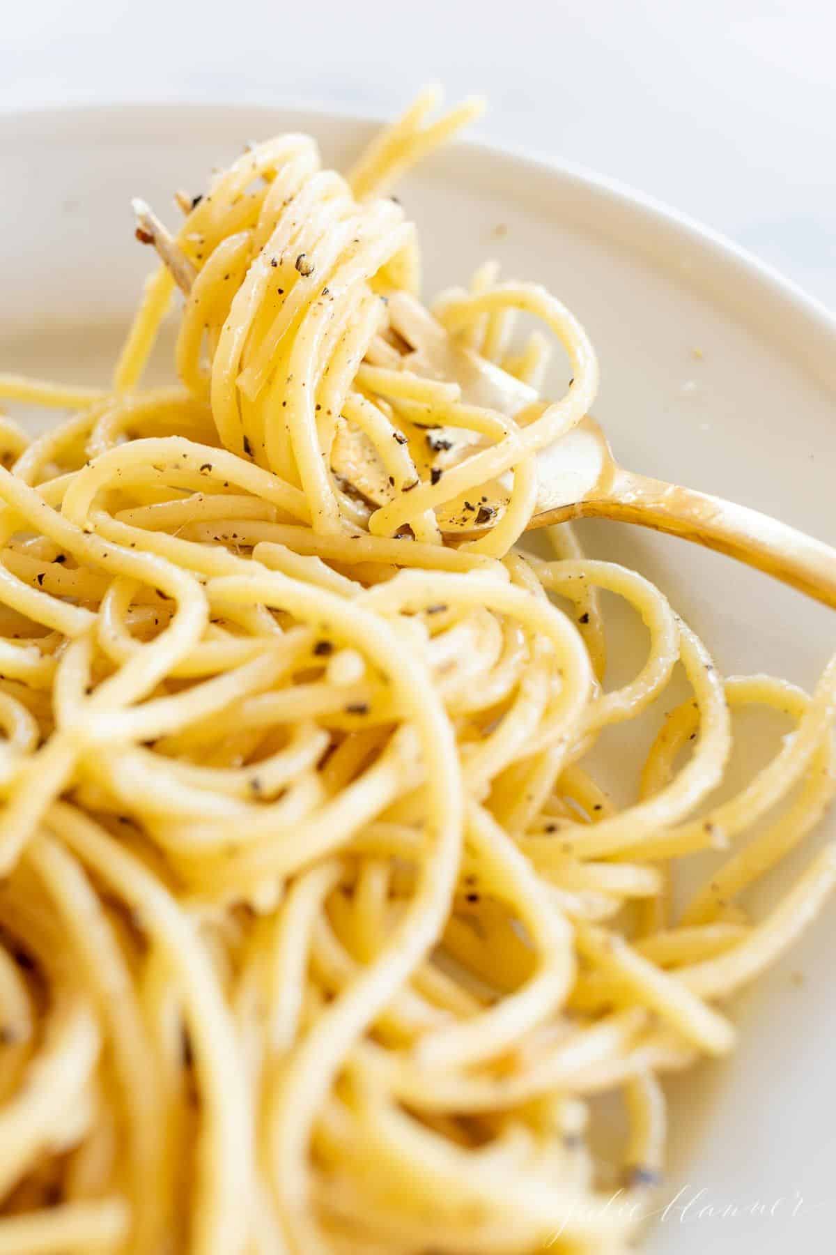 图片展示了一个白色的盘子里装满了意大利面条，金色的叉子在盘子的一边旋转着意大利面。gydF4y2Ba