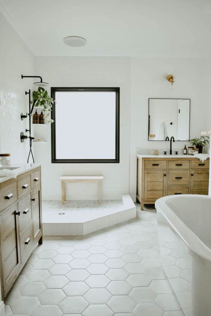 一间白色的浴室，带有现代化的浴缸和六边形瓷砖地板。
