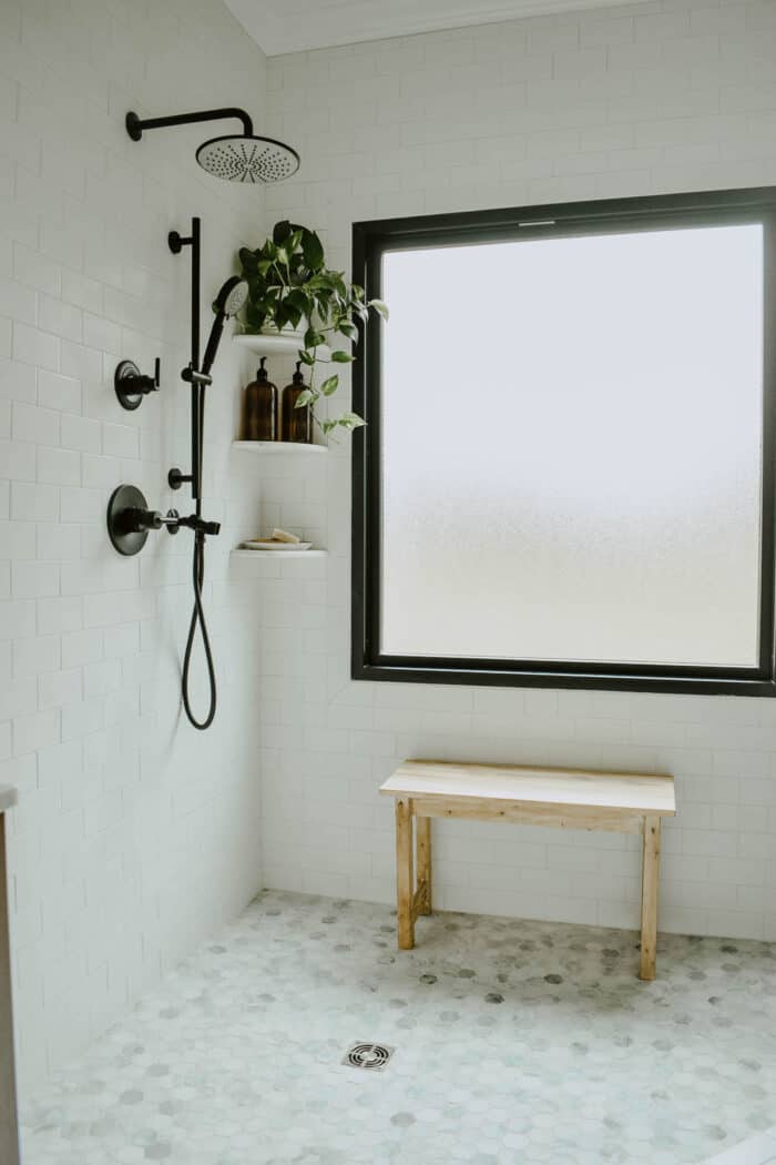 一间白色的浴室，带有现代化的浴缸和六边形瓷砖地板。