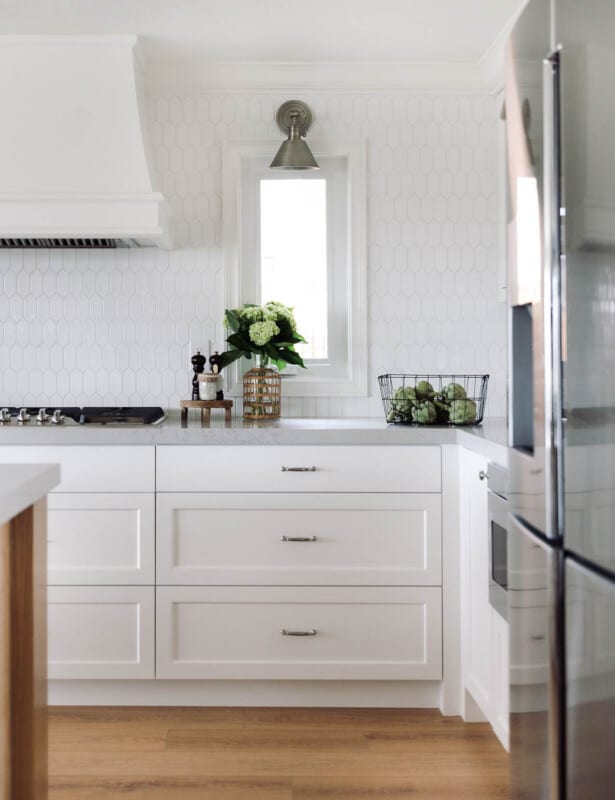 带有白色六角瓷砖后挡板和白色橱柜的厨房。