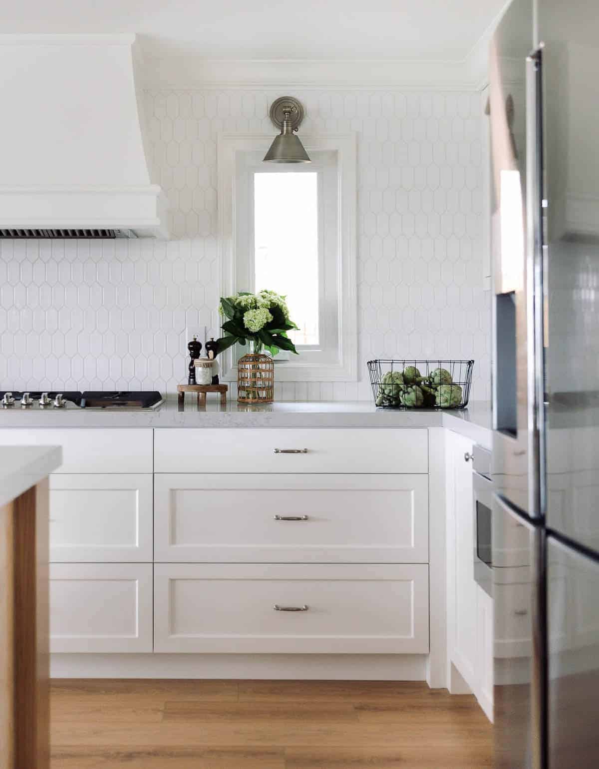 厨房有白色六角形瓷砖后挡板和白色橱柜。