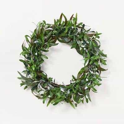 A faux olive branch wreath on a white surface