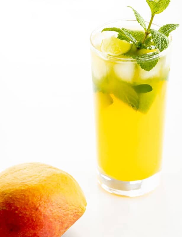 芒果莫吉托（Mango Mojito）的食谱在透明的玻璃杯中，上面饰有薄荷的小树枝，芒果在前景中。