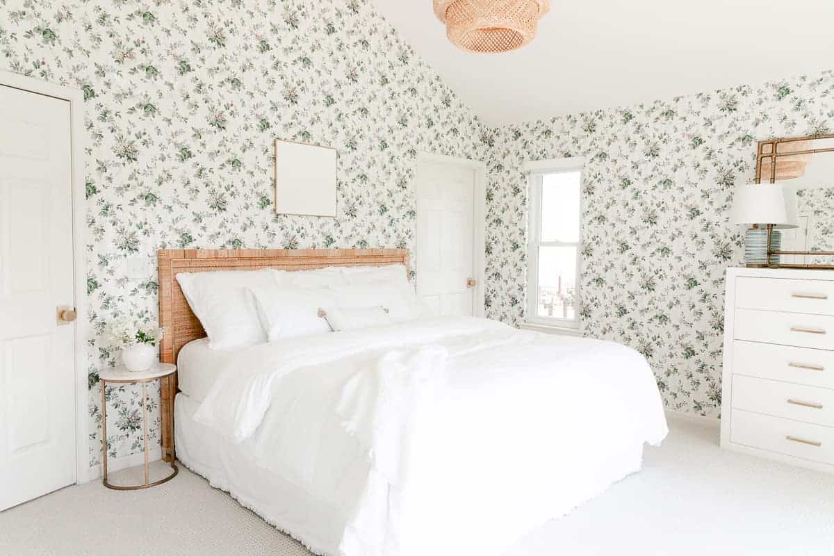 有壁纸和白色床上用品的卧室，床上有白色艺术品