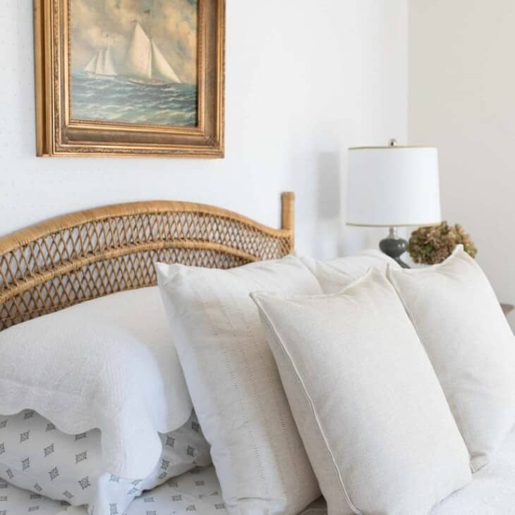 一间带中立床上用品的卧室，藤床和床头板上的帆船艺术品。