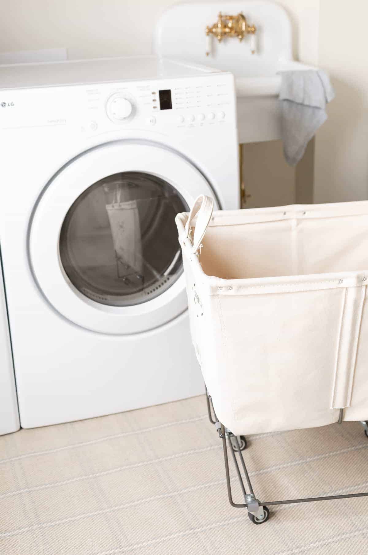 一个滚动的洗衣篮，背景有洗衣机和烘干机。