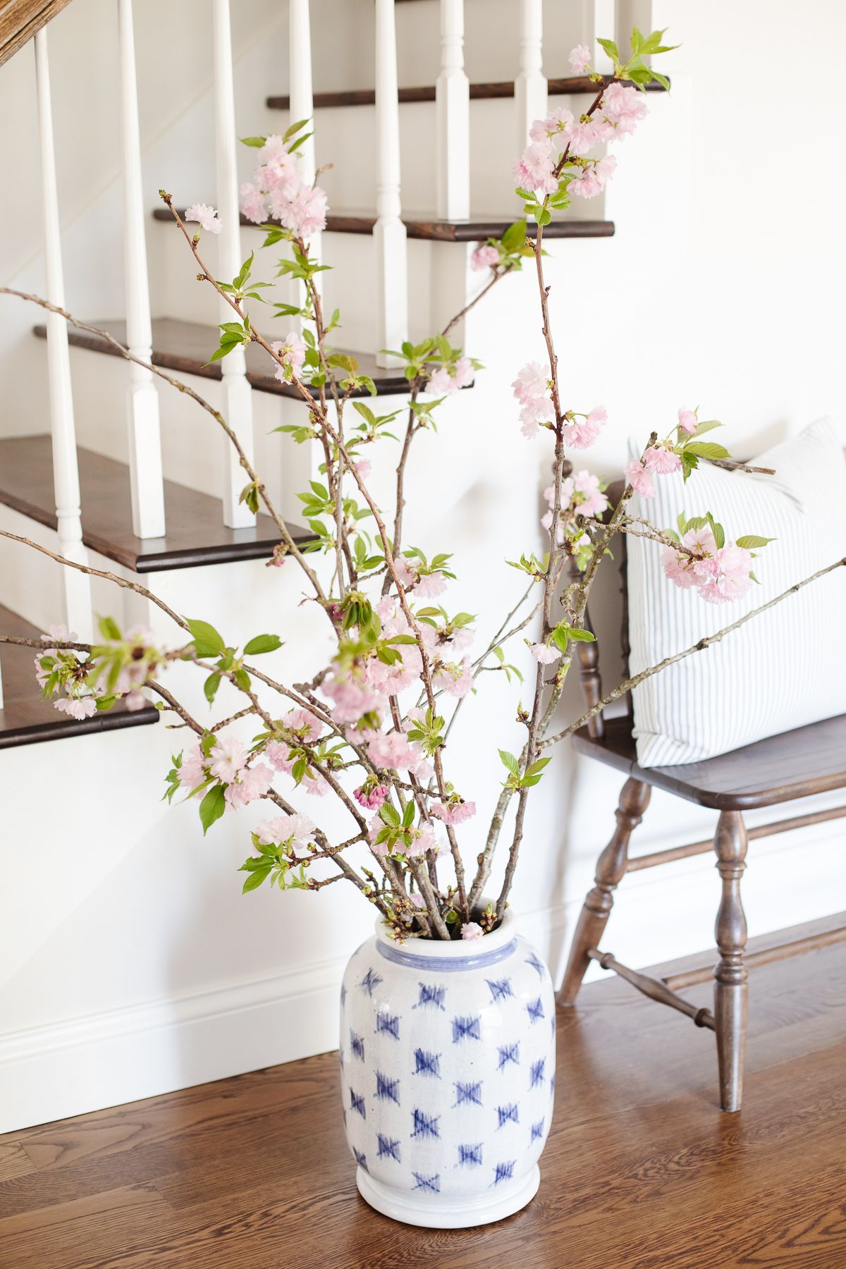 在楼梯后面的入口，一个蓝白色的花瓶里，盛开着粉红色的树枝