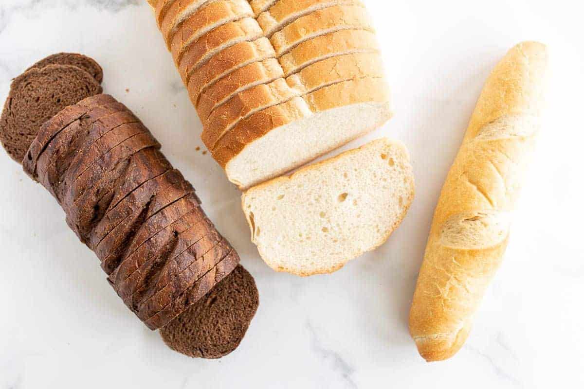 三个不同的面包放在大理石表面上，在一个关于烤奶酪最好的面包的帖子里。