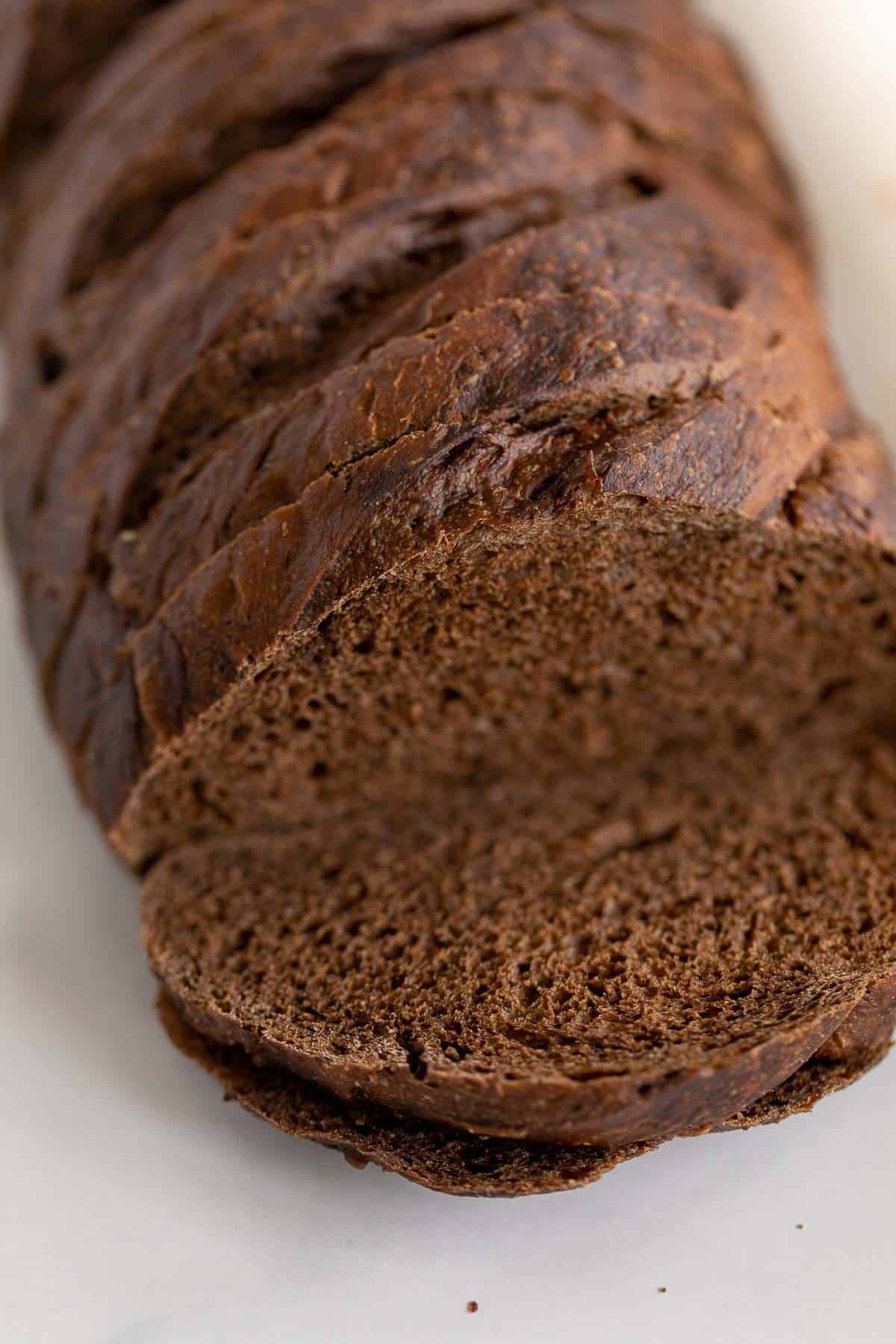一条黑麦面包，切片放在大理石台面上。