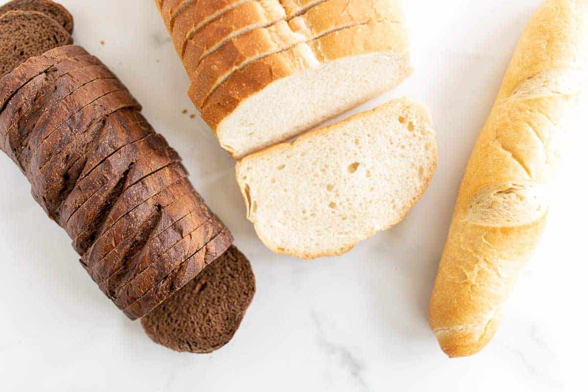 三个不同的面包放在大理石表面上，在一个关于烤奶酪最好的面包的帖子里。