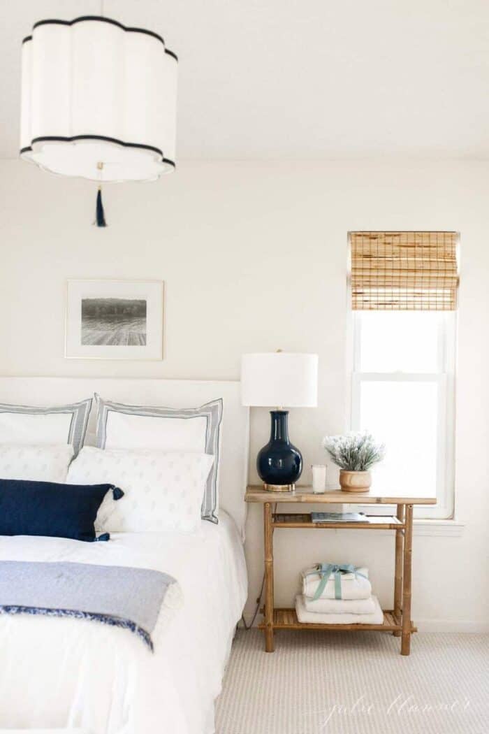 一间小卧室，有一盏海军蓝和白色相间的台灯和头顶的吊坠
