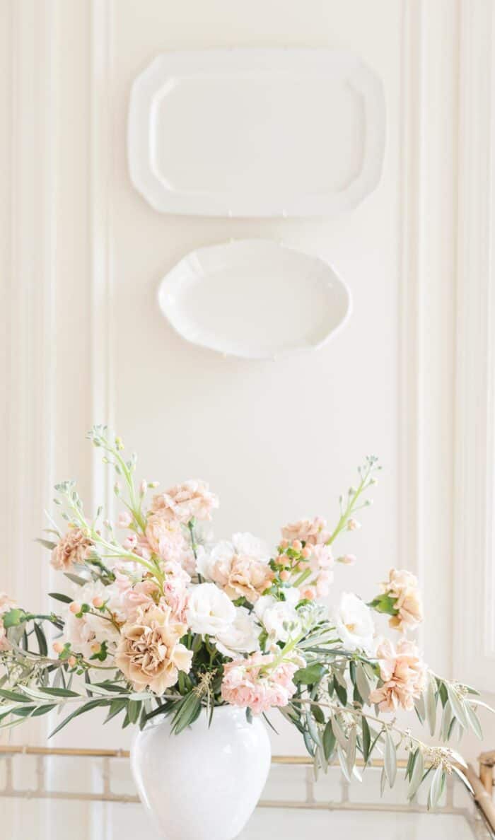 古董康乃馨，股票和绿色植物在白色背景的白色花瓶。