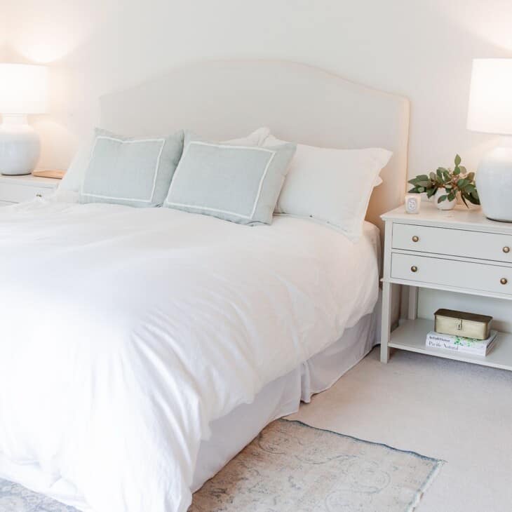 一间白色的卧室，床下铺着一张复古的卧室地毯。
