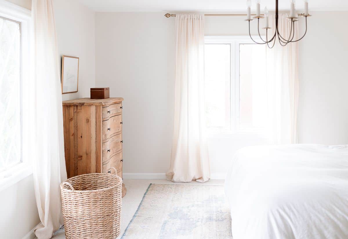 一个白色卧室，带木制梳妆台和床单的右尺寸地毯。