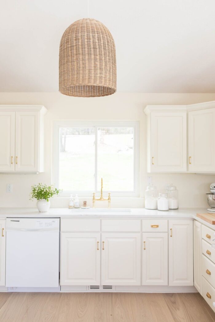 漆成奶油色的厨房，配有篮子式灯具和石英台面。