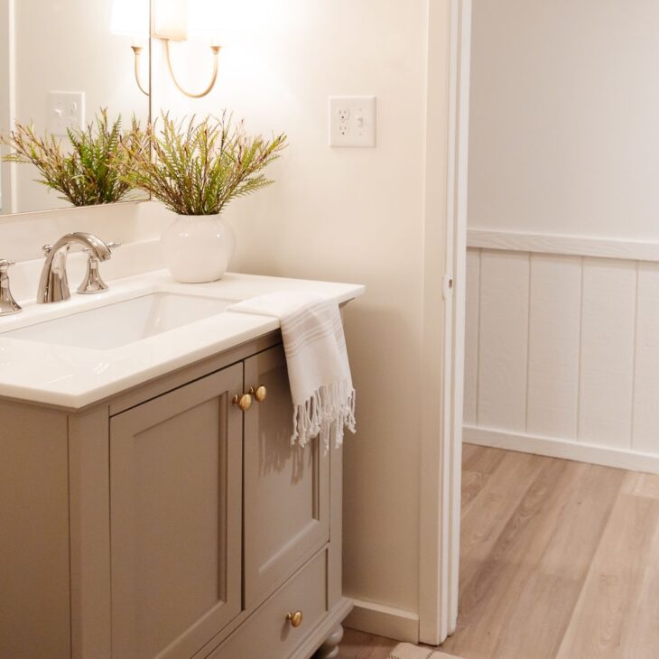 一间小浴室，有金色的壁龛、灰色的梳妆台和漆成云白色的墙壁