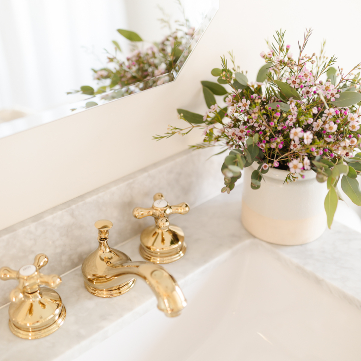 大理石水槽上的广泛的黄铜浴室水龙头和花朵