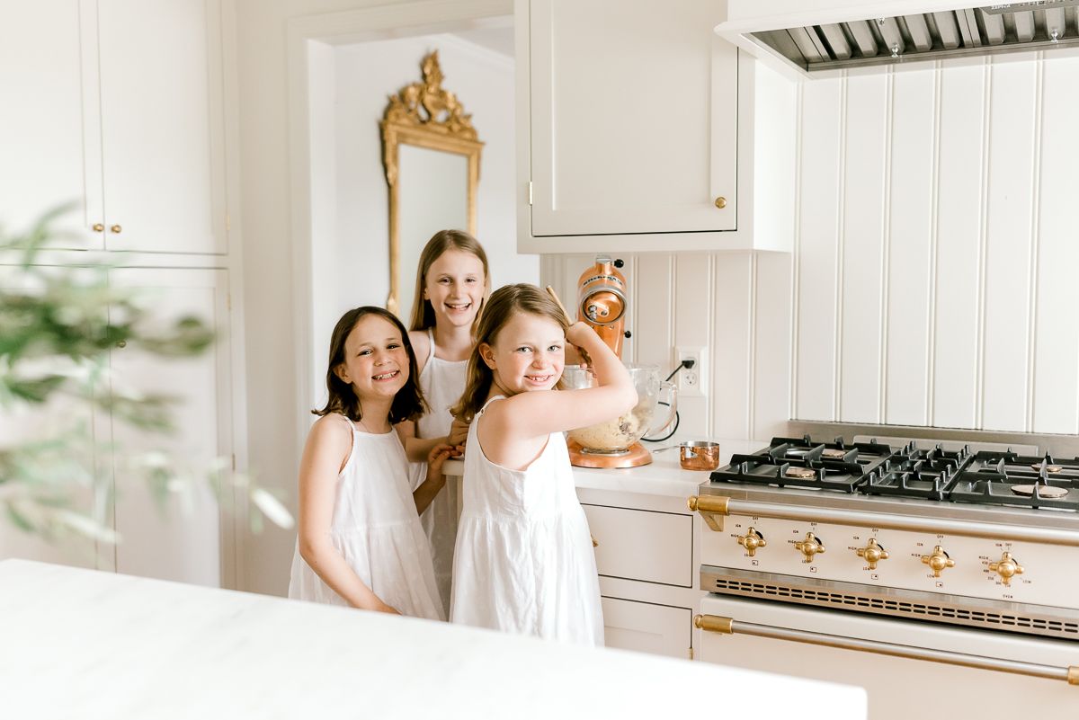 三个穿着白裙子的小女孩在白色的厨房里