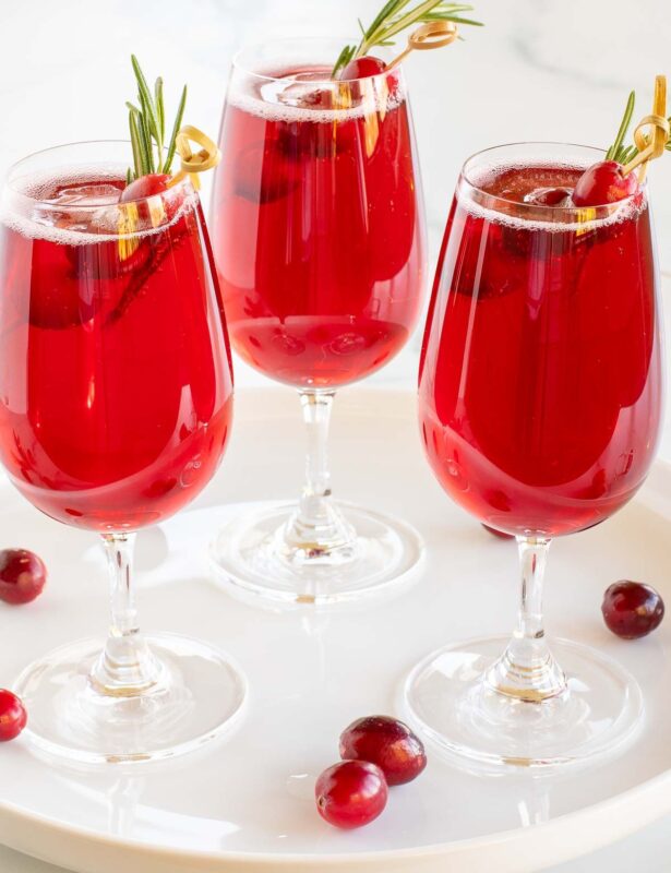 一品红饮料放在白色托盘上，蔓越莓和迷迭香作为装饰