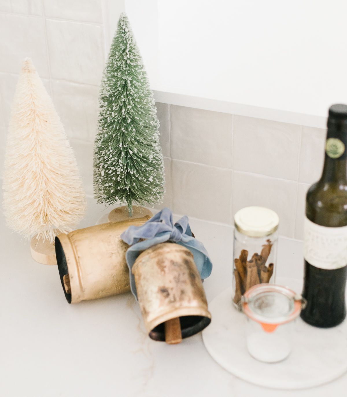 厨房柜台上陈列着圣诞铜铃和瓶刷树