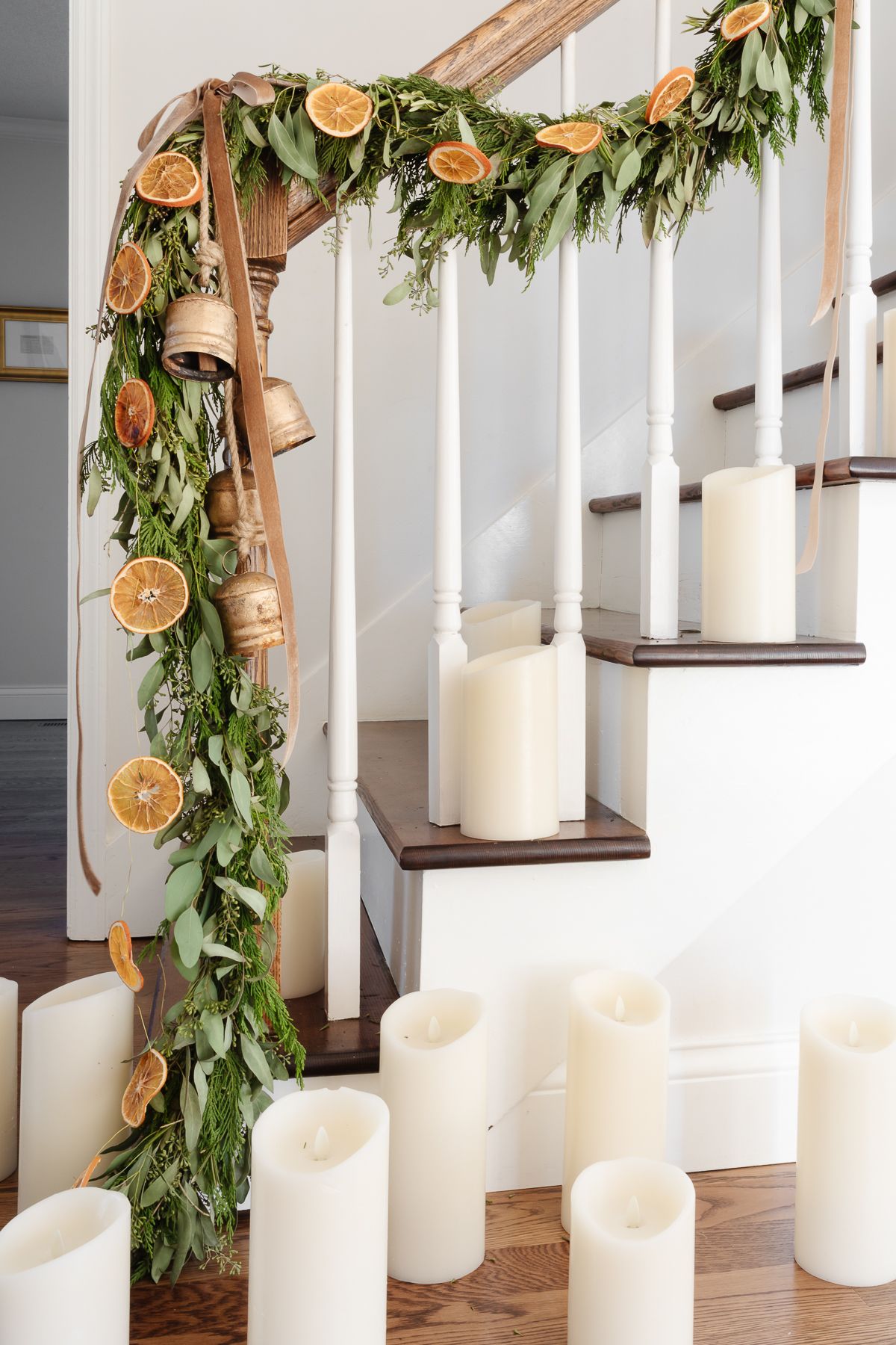 楼梯上的橙色花环，上面有常绿花环、天鹅绒缎带和铜铃。