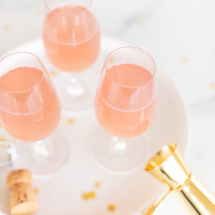 3杯桃红色香槟玛格丽塔酒在一个白色盘子与金五彩纸屑周围GydF4y2Ba