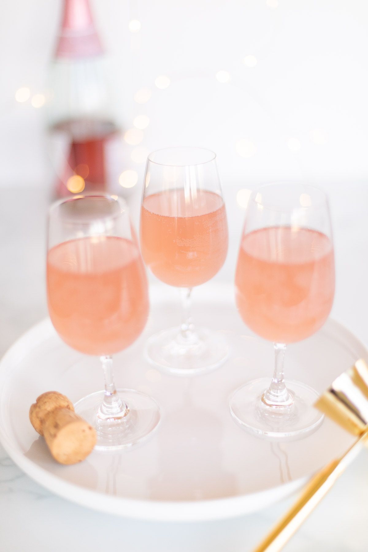 3杯桃红色香槟玛格丽塔酒在一个白色盘子与金五彩纸屑周围GydF4y2Ba