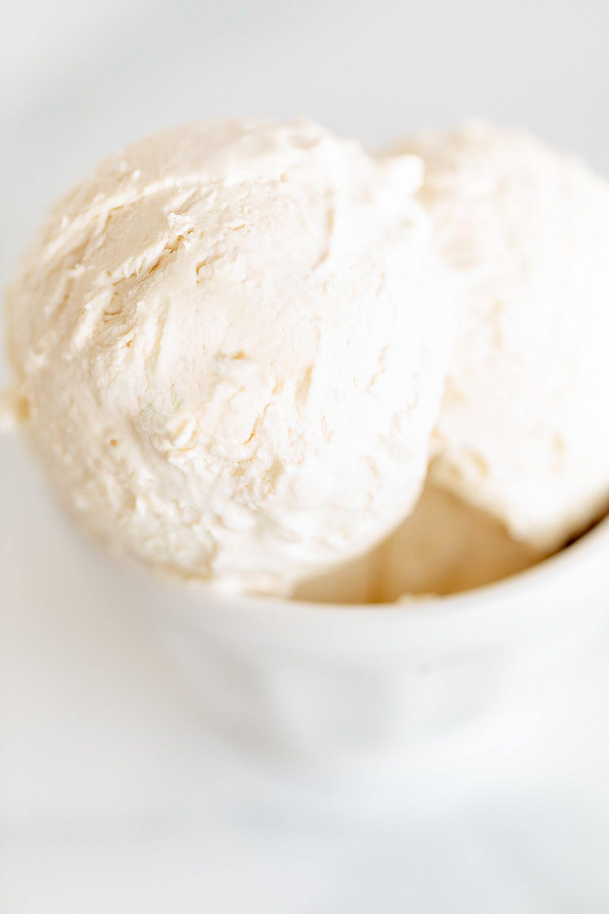 一个大理石表面的白色碗，盛满了冰冻的马斯卡彭冰淇淋