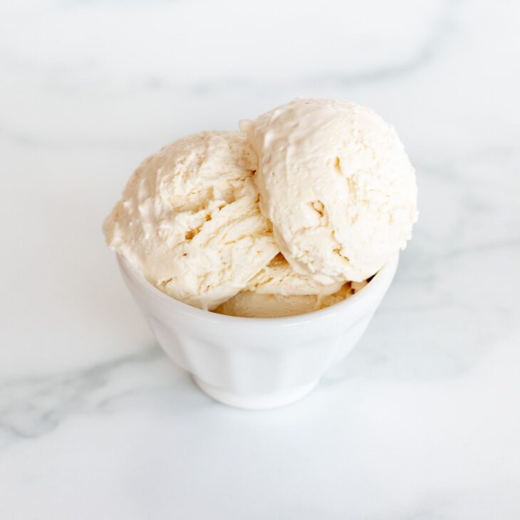 一个大理石表面的白色碗，盛满了冰冻的马斯卡彭冰淇淋