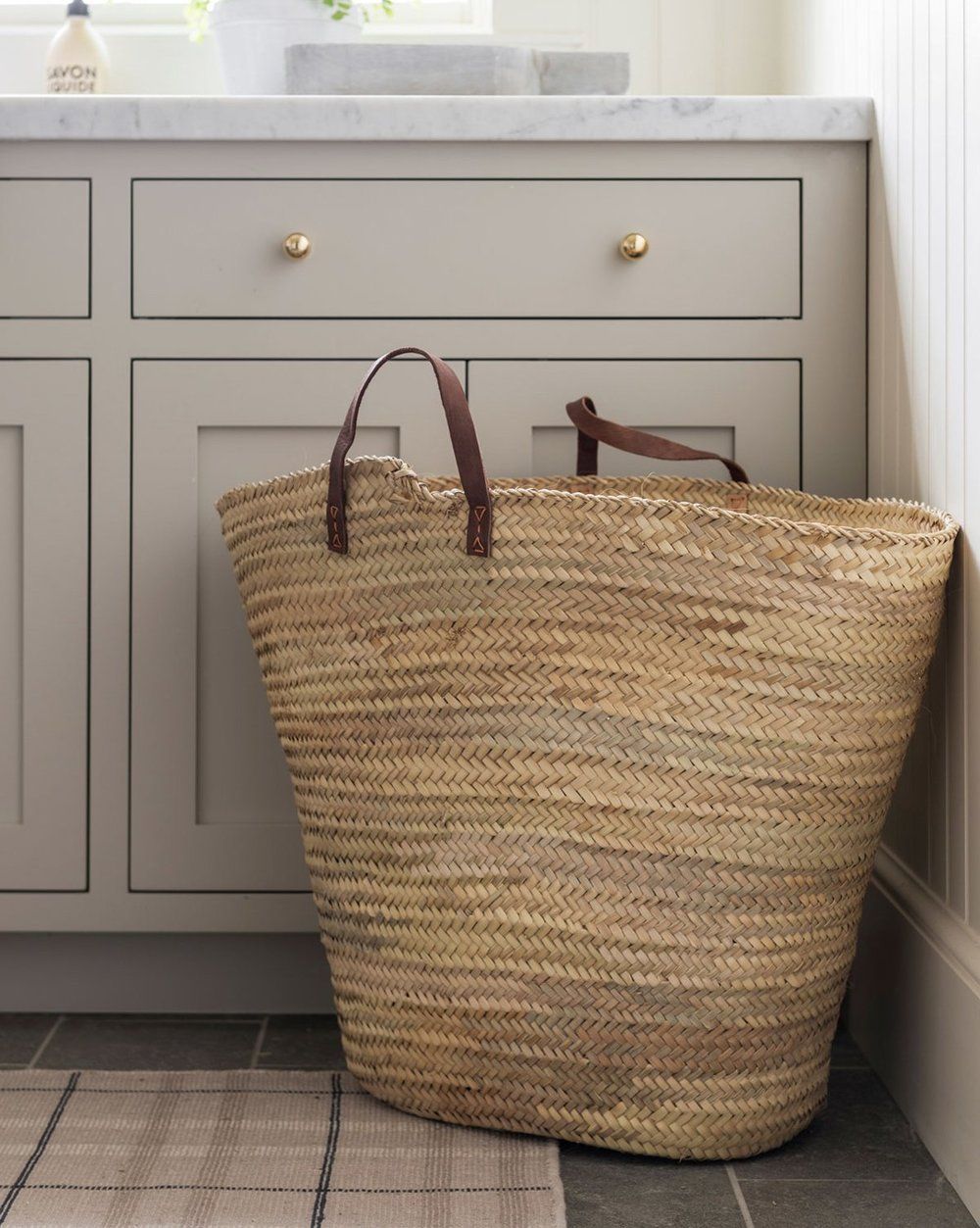 一个洗衣房橱柜，用珍珠锡粉，前面有一个稻草手提袋。
