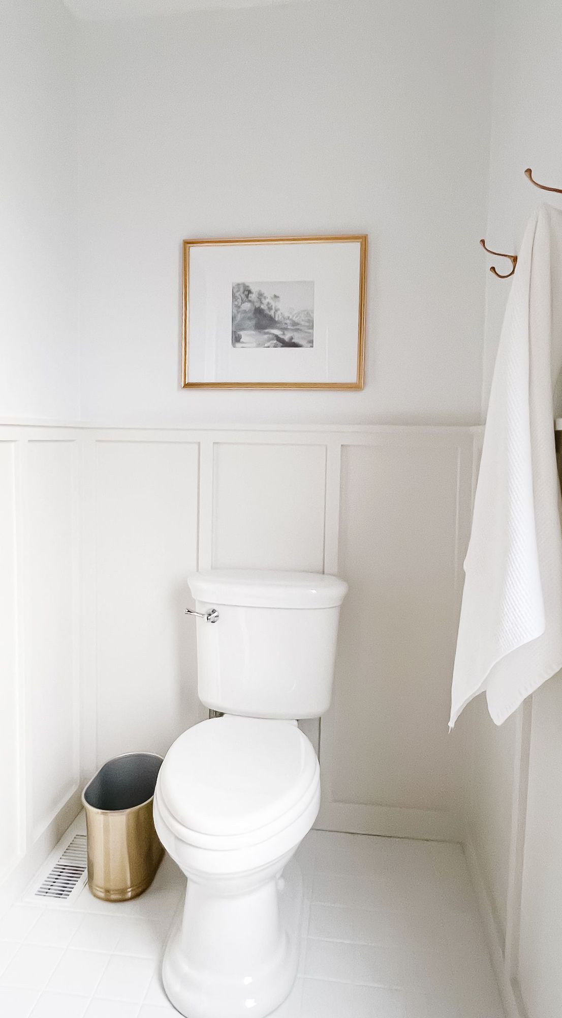 一间白色和灰色的浴室，空间周围有护壁板，上面是白色的油漆。