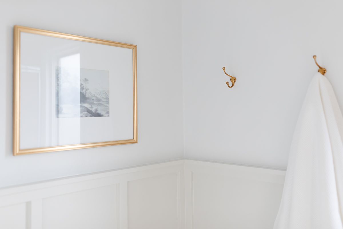 一间小浴室，木板和木条漆成经典灰色，上层墙壁漆成本杰明摩尔装饰公司的白色。