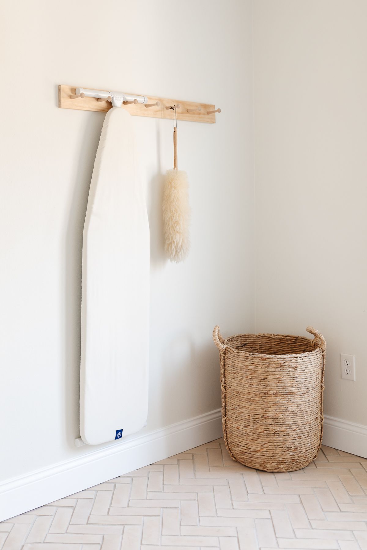 一个带人字形地板的洗衣房的角落和带有熨衣板的钉轨。