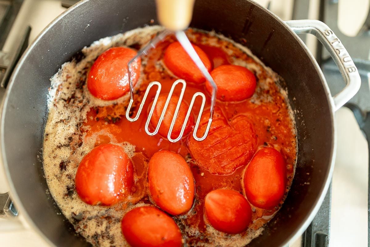 将圣马尔扎诺番茄放入铸铁锅中，用工具开始捣碎它们。gydF4y2Ba