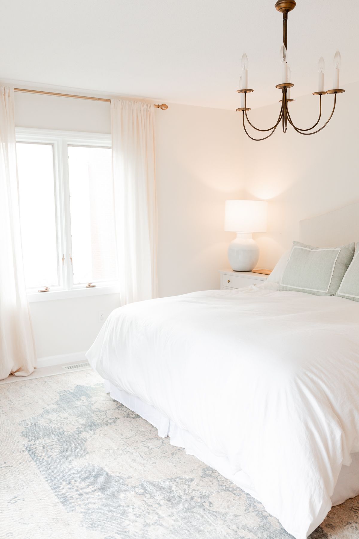 白色卧室，地板上有蓝色的传统地毯