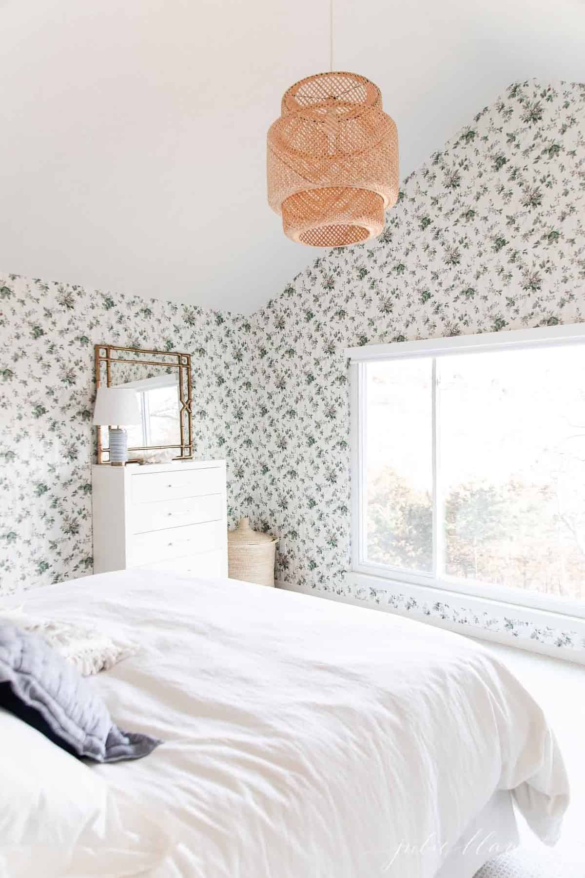 一间带有木制装饰的白色卧室和一张陈述花卉墙纸。