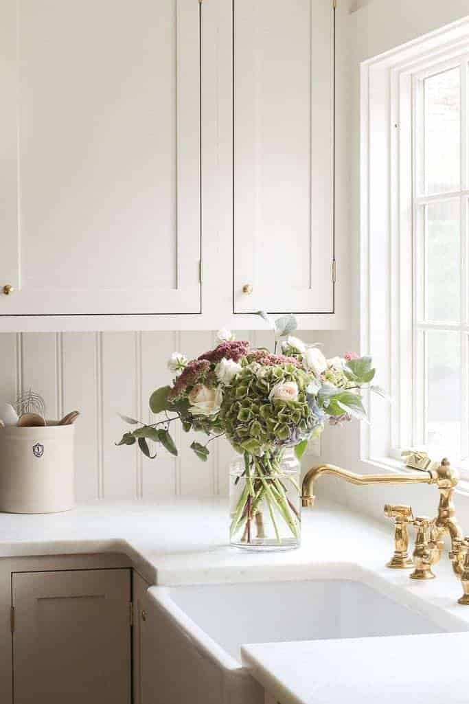 厨房里镶有奶油色的橱柜，配有大理石柜台和黄铜水龙头。