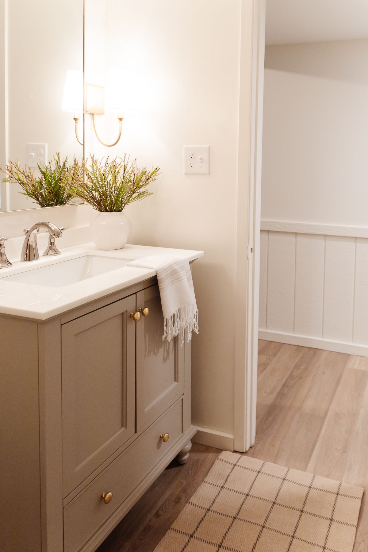 一间小浴室，有金色的壁龛、灰色的梳妆台和漆成云白色的墙壁